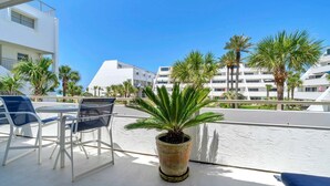 A balcony with a potted plant, a table, and chairs. - Aegean 215 – Updated Condo with Private Balcony & Beach Access (Destin)