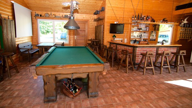 A pool table in a wooden room with a bar area and stools. - Messe-Hotel Waldruhe (Giesen)