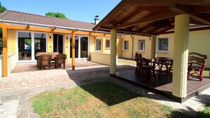 A covered patio area with a brick floor and wooden furniture. - Messe-Hotel Waldruhe (Giesen)