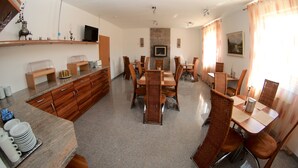 A spacious dining area with multiple tables and chairs, a television, and a fireplace. - Messe-Hotel Waldruhe (Giesen)