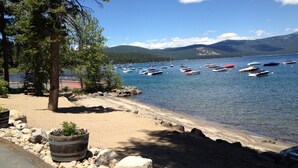 Vista panorámica de un lago con barcos, una playa de arena y un área boscosa.