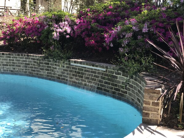 A swimming pool with a brick wall and a waterfall feature.
