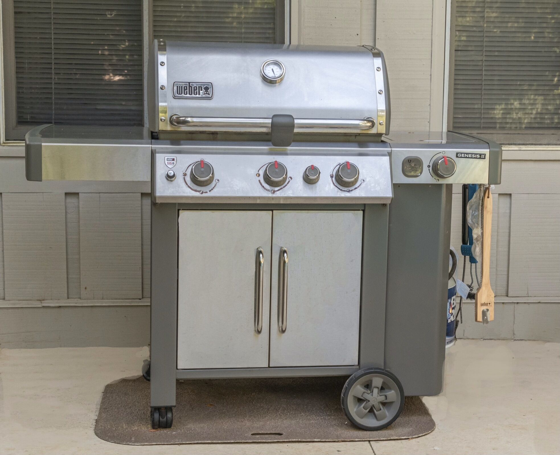 A portable Weber Genesis II grill with four burners, a thermometer, and a side shelf.