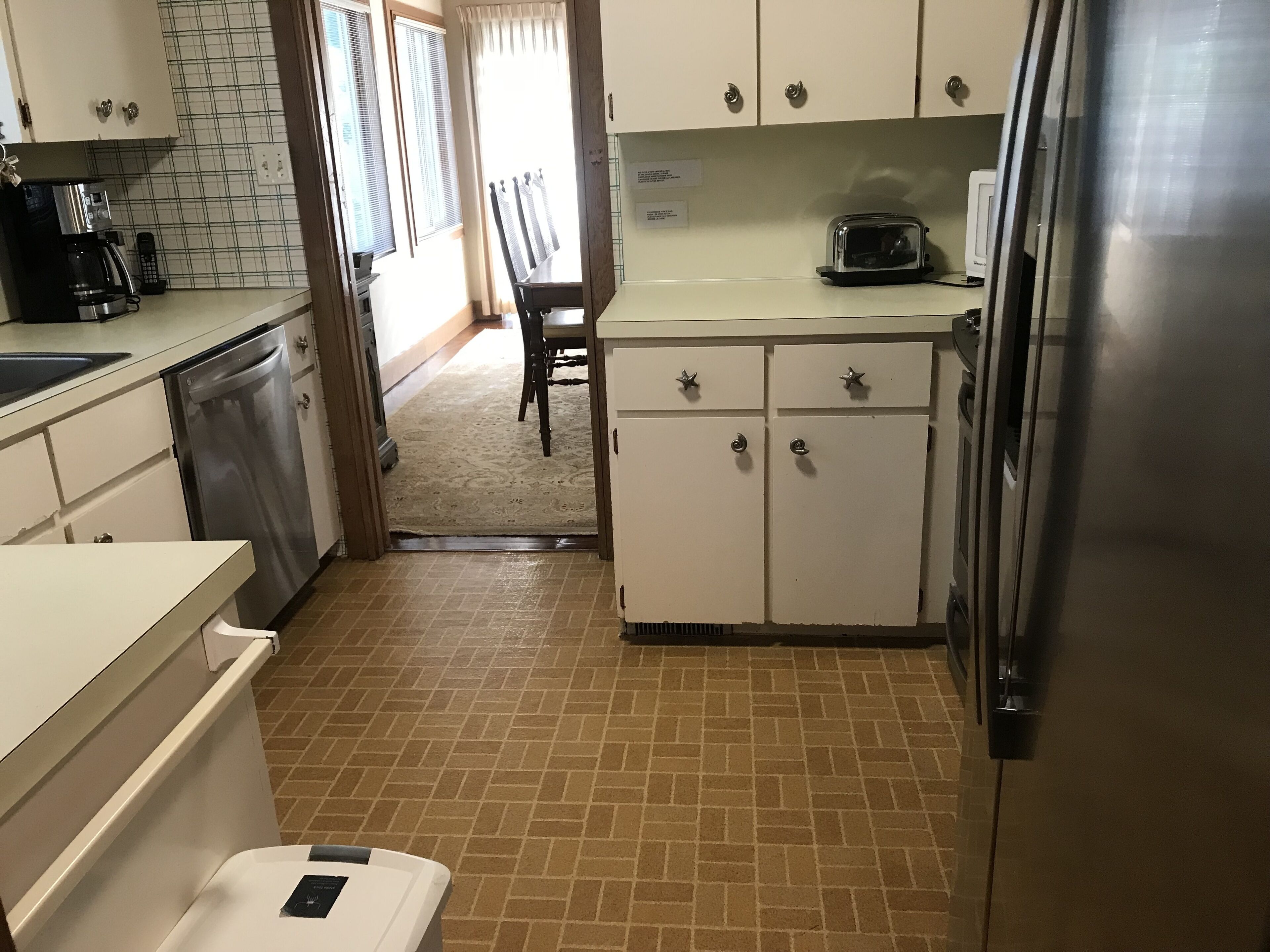 Una cucina con mobili bianchi, un frigorifero in acciaio inossidabile, un tostapane e una macchina da caffè.