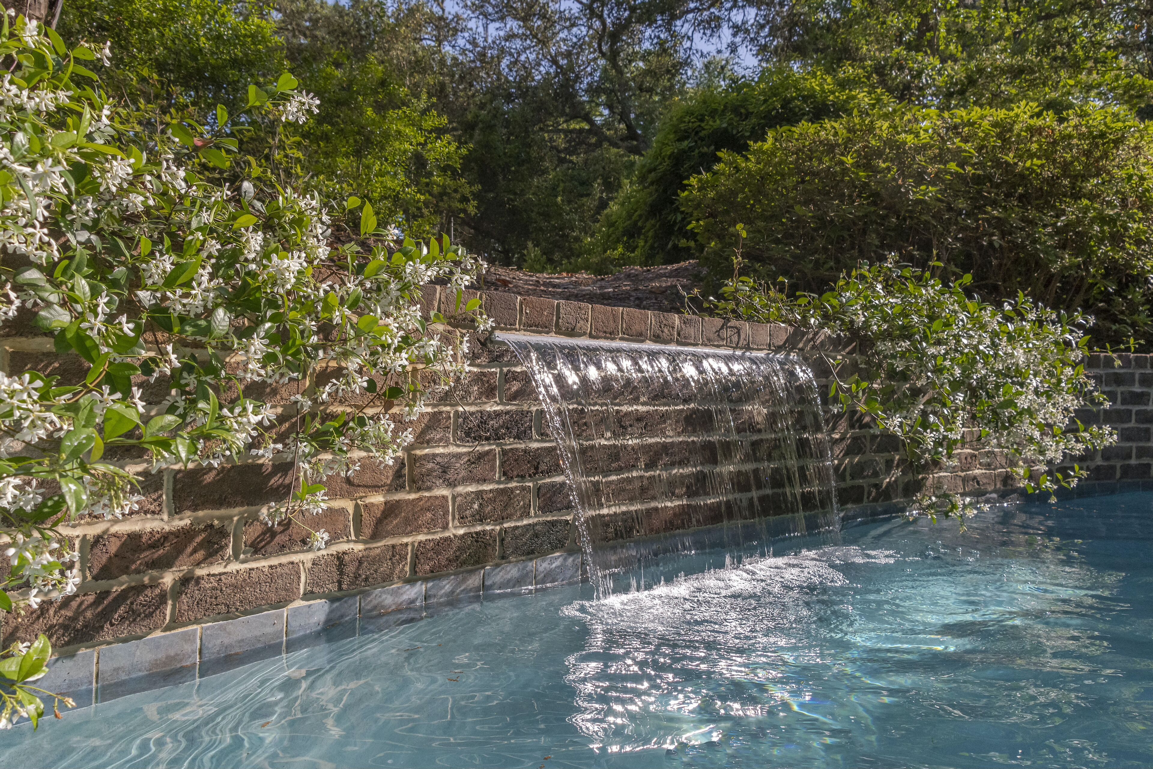 Een zwembad met een waterval, omringd door weelderige begroeiing.