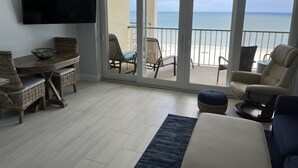 Ein Zimmer mit einer großen Glasschiebetür, die auf einen Balkon mit Blick auf den Strand führt.