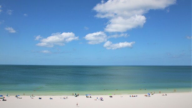 Ein Strand mit blauem Himmel und ruhigem Wasser.