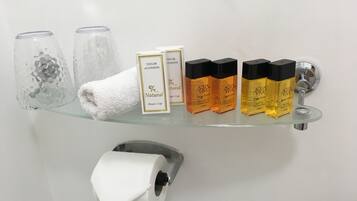 Une étagère de salle de bain avec un bonnet de douche, deux bouteilles de shampoing et un rouleau de papier toilette.