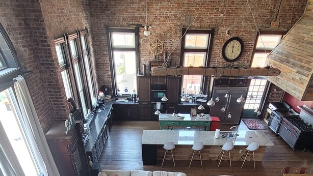 Uma sala de estar ampla com cozinha, janelas grandes e pé direito em estilo loft.