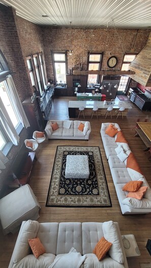 A spacious living area with a kitchen, large windows, and a loft-style ceiling. - Indoor Basketball Court, Movie Theatre & Rooftop-Private 3rd floor Penthouse! (Sandusky)