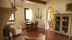 A dining area with a table and chairs, a cabinet with dishes, and a staircase. - Alla Cedrara agriturismo (Ferrara)