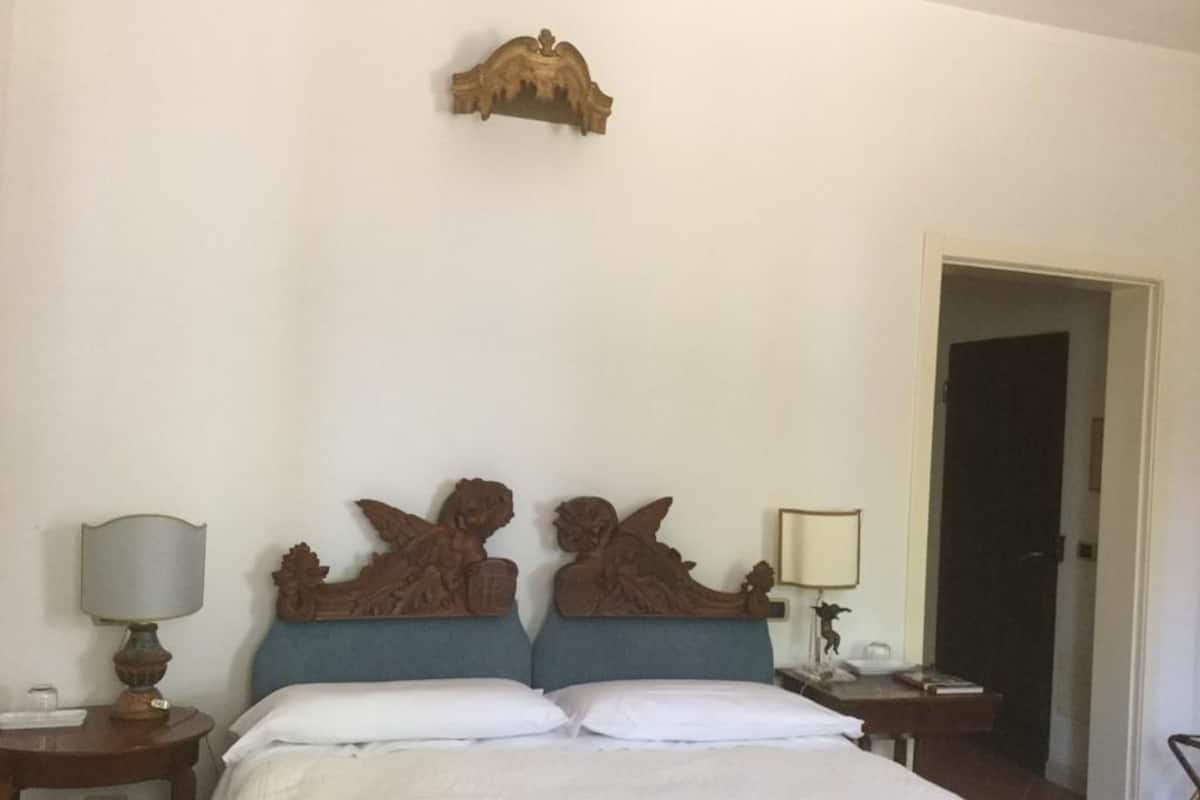 A hotel room with a bed, two nightstands, and a door.