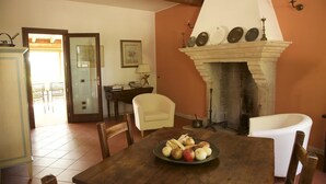 A dining area with a wooden table, chairs, and a fireplace. There is a plate of fruit on the table. - Alla Cedrara agriturismo (Ferrara)