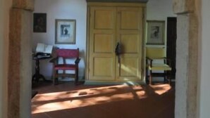 An arched doorway leading to a room with a tiled floor, a wooden bench, and a yellow door. - Alla Cedrara agriturismo (Ferrara)