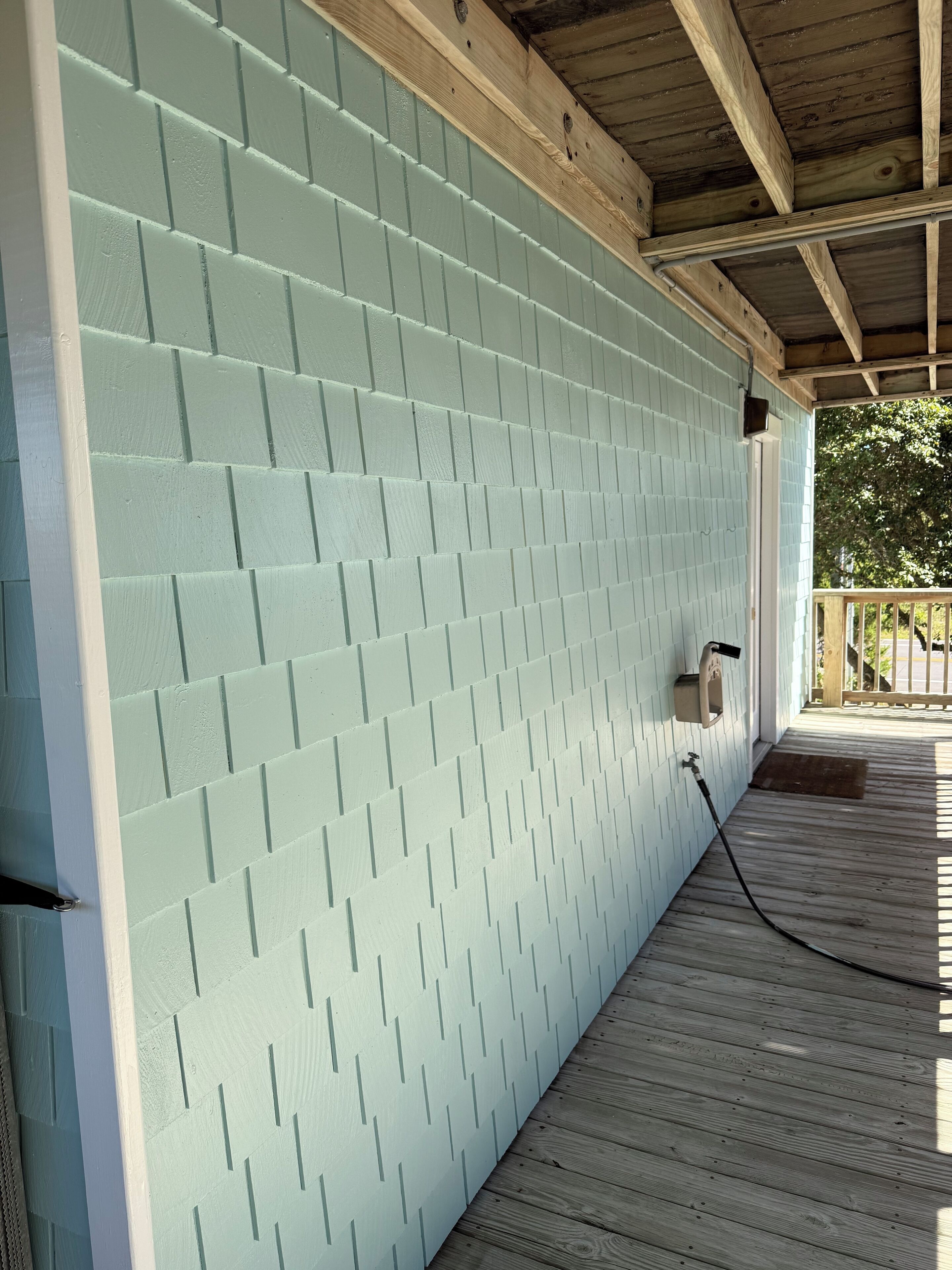 A covered porch with a light blue brick wall and wooden beams.