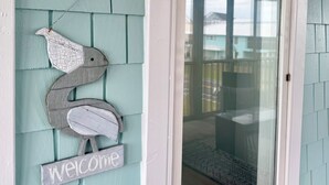 A teal exterior wall with a welcome sign and a decorative bird. - Sunset Dream - sunset view, short walk to beach (Surf City)
