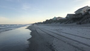 A beach with a sandy shore, a few people, and houses with stairs leading down to the beach. - Sunset Dream - sunset view, short walk to beach (Surf City)
