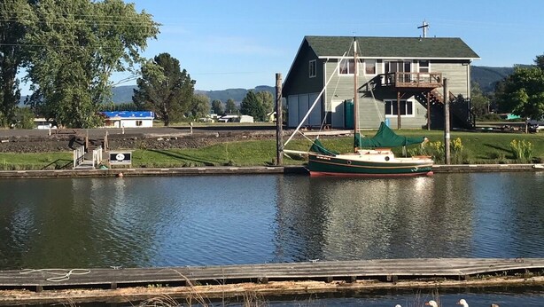 A house by a calm lake with a dock and a boat.