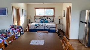 A bedroom with a bed, bedside tables, a lamp, a radiator, and a refrigerator.
