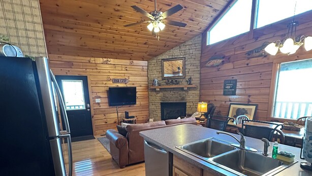 A kitchen with wooden cabinets, a refrigerator, a dishwasher, a sink, and a ceiling fan.