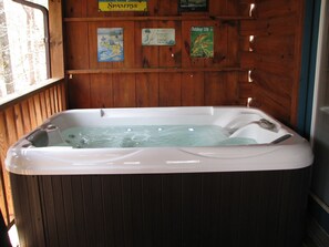 Un bain à remous dans un chalet en bois, avec des murs en bois et une fenêtre.