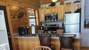 A wooden-paneled kitchen with a wooden dining table, two chairs, and a refrigerator.