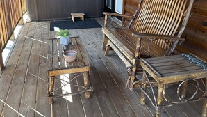 A wooden deck with a hot tub, a wooden bench, and a chair.