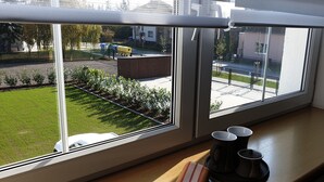 A window with a view of a street, a parked car, and a building across the road. - Apartma Transpet (Kostelec na Hané)