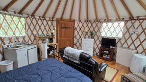 Interieur van een joert met een bed, kitchenette en een televisie.