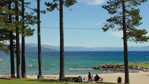 Una playa con mesas de picnic y un rompeolas rocoso.