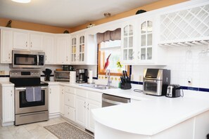 Een moderne keuken met witte kasten, roestvrijstalen apparatuur en een groot eiland.