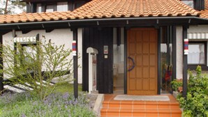 Una casa con techo de tejas, puerta de madera y un conjunto de escalones que conducen a la entrada.