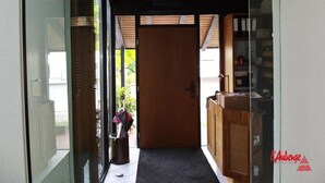 Un pasillo con una puerta de madera, una puerta de cristal y una pequeña alfombra que conduce a una habitación.