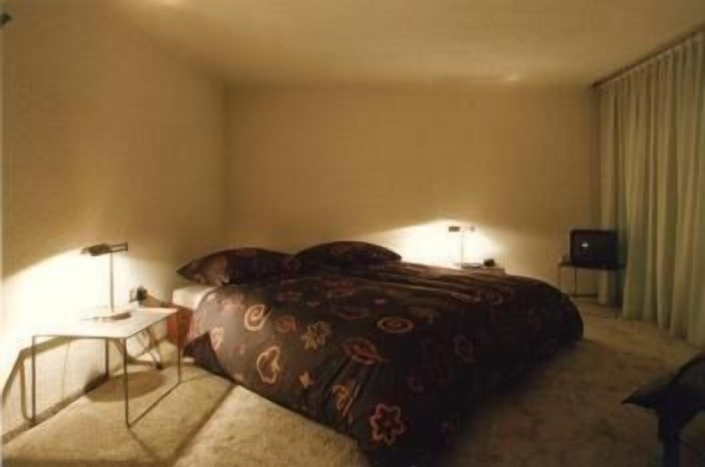 A hotel room with a bed, a desk, and a chair.