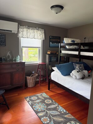 Une chambre avec un lit superposé, un bureau, une commode, une fenêtre avec des rideaux, un tapis et un luminaire au plafond.