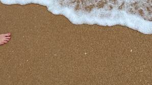 Ein Sandstrand mit ankommenden Wellen.