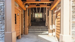 A narrow hallway with wooden doors and a staircase leading to a second floor. - Mammoth Gateway Village #1 - Updated Townhome-Walk To Village 3 Bed+Loft, Sleeps 10 Private Hot Tub (Mammoth Lakes)