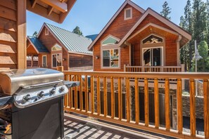 A wooden cabin with a balcony, a grill, and a stone wall.