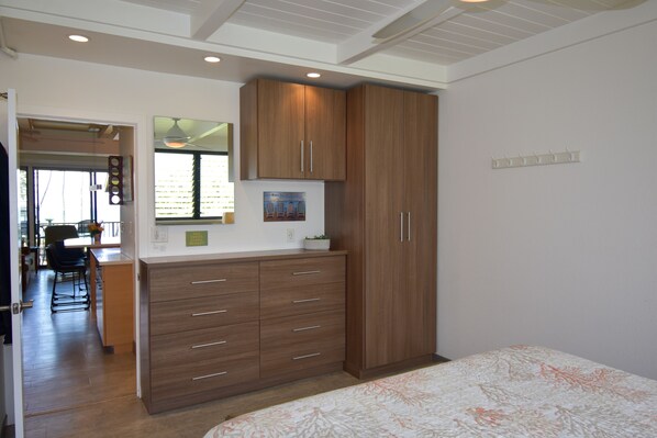 A bedroom with a bed, wooden wardrobe, and a desk with a chair.