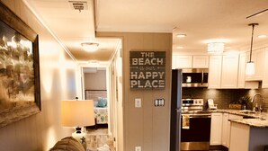 A modern living room with a sofa, pillows, and a kitchen area in the background. - Gorgeous 5 Star! Oceanblock Midtown condo directly Across from Convention Center (Ocean City)