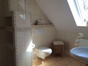 A small, compact bathroom with a toilet, a sink, and a shower area. - Friesenglück Kolkerheide (Kolkerheide)