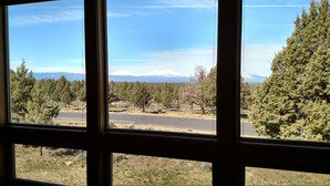 Vista a través de una ventana que muestra un camino bordeado de árboles y una montaña al fondo.