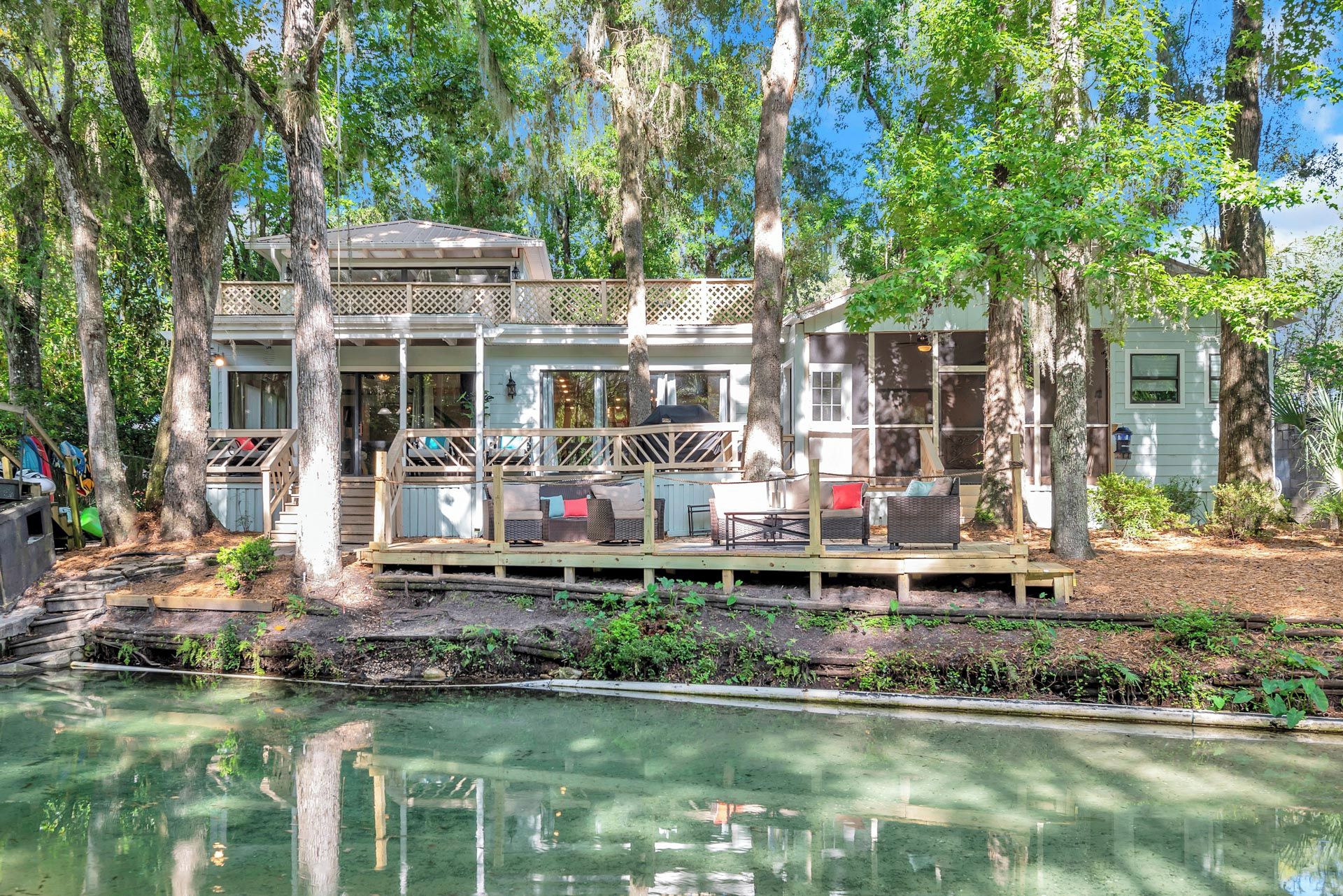 A house with a deck, outdoor seating, and a pool.
