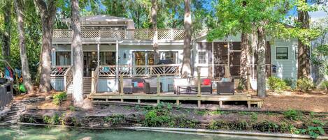 A house with a deck, outdoor seating, and a pool.