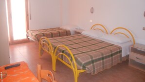 Una habitación con dos camas, una mesita con un control remoto y una silla.