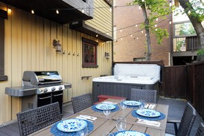 An outdoor patio with a grill, hot tub, and dining setup. - Entire large home- Luxe, Walk to lift & town! Game room, hot tub (Park City)