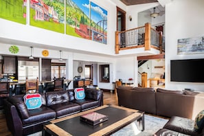 A spacious living area with a high ceiling, a dining area, and a staircase leading to an upper level. - Entire large home- Luxe, Walk to lift & town! Game room, hot tub (Park City)