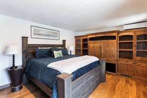 A bedroom with a large bed, wooden wardrobe, and a nightstand with a lamp. - Entire large home- Luxe, Walk to lift & town! Game room, hot tub (Park City)