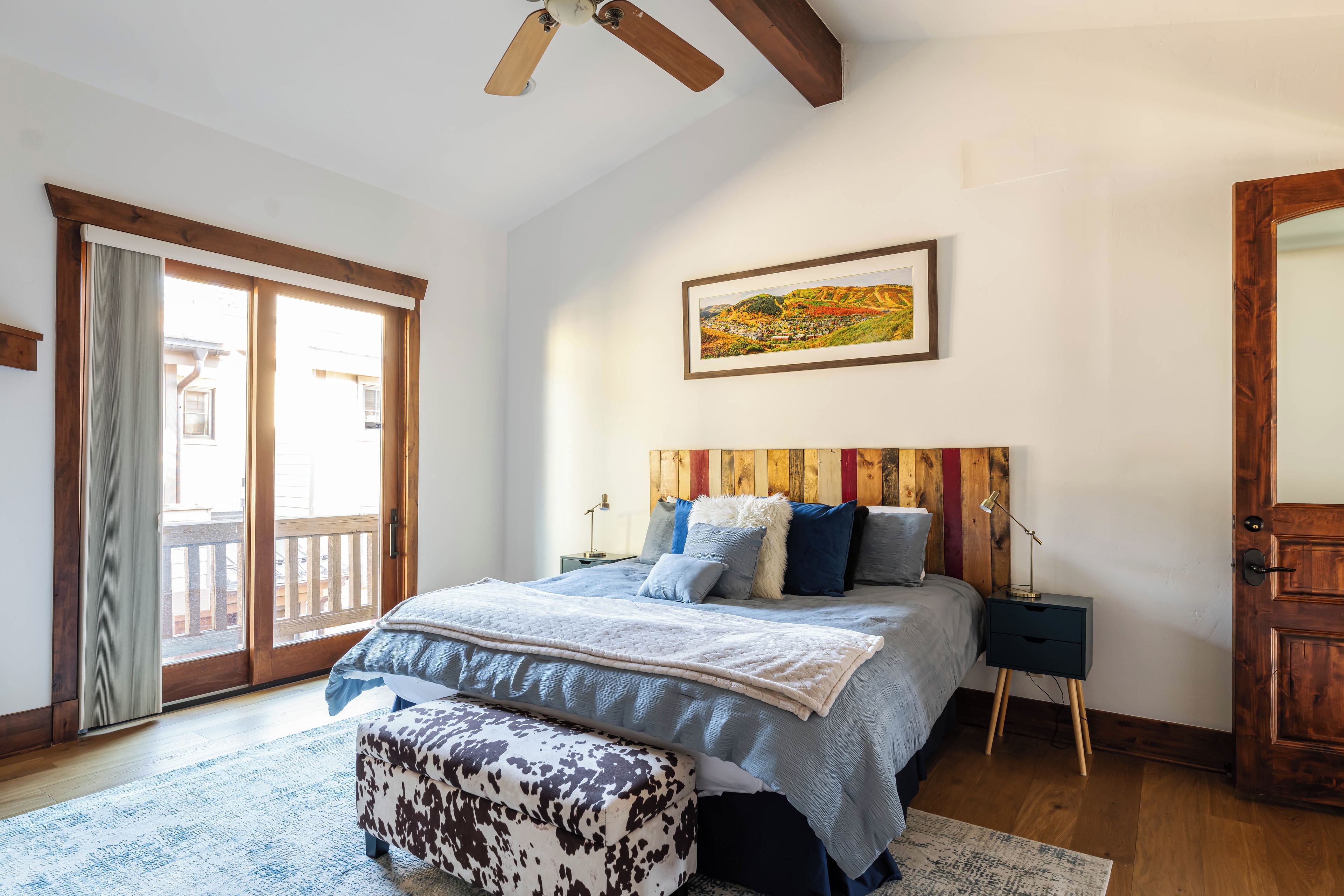 Ein Schlafzimmer mit einem Bett, Nachttischen, einem Fenster und einem Deckenventilator.