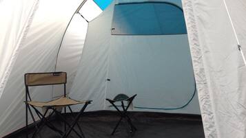 A tent with a blue and white color scheme, two folding chairs, and a visible entrance.